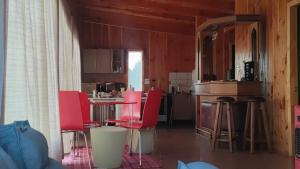 a kitchen with red chairs and a table in a room at Cabaña en Chacao Viejo, Chiloé - Tranquilidad y Frente al mar in Ancud