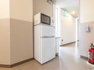 a white refrigerator with a microwave on top of it at Tabist New Gekkoen in Shimminatomachi