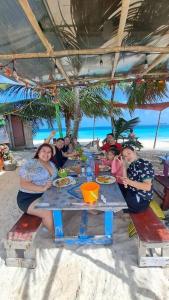 a group of people sitting at a table on the beach at hospedaje en las islas de San blas habitacion privado con baño compartido in Achoertupo