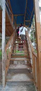 a man walking down a wooden stairs in a building at hospedaje en las islas de San blas habitacion privado con baño compartido in Achoertupo