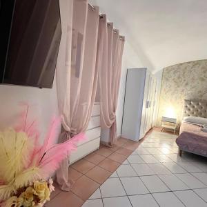 um quarto com cortinas cor-de-rosa, uma televisão e um sofá em Aurora's Home em Nápoles