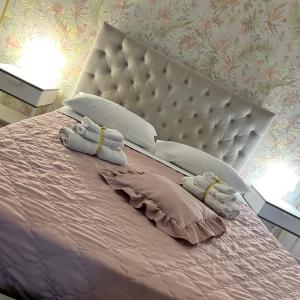 um quarto com uma cama grande com lençóis e almofadas cor-de-rosa em Aurora's Home em Nápoles