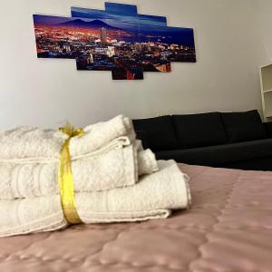 um quarto com uma cama com toalhas e um sofá em Aurora's Home em Nápoles