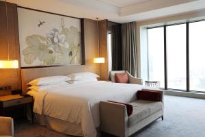 a hotel room with a large bed and a chair at Sheraton Shanghai Jiading Hotel in Jiading