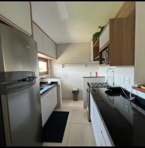 a kitchen with a refrigerator and a stove top oven at Village OAHU Imbassaí in Matta de São João