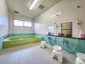 a bathroom with a green tub and a toilet and a sink at Yukikan in Yuki