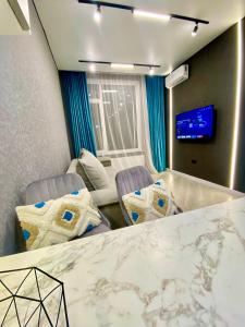a room with two chairs and a table and a tv at Landmark Astana 2 комнатные апартаменты in Astana