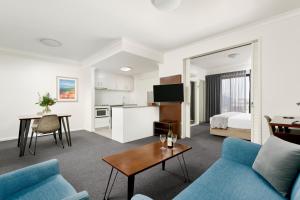 a living room with a blue couch and a table at Quest West End in Perth