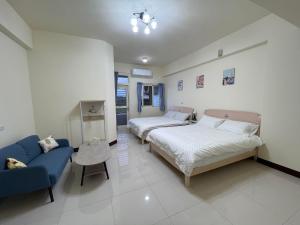 花蓮市にある凱莉民宿-花蓮包棟のベッドルーム1室(ベッド2台、青いソファ付)