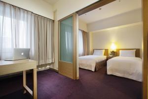 a hotel room with two beds and a laptop on a desk at Howard Civil Service International House in Taipei