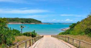 a dirt road leading to a beach with a fence at Ap Enseada Azul ES Pé na Areia in Guarapari