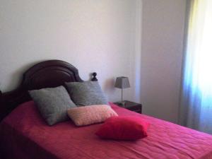 a bed with a pink blanket and pillows on it at Casa Ameijeira in Lagos