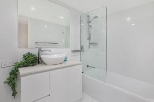 a white bathroom with a sink and a shower at Beachside Resort Kawana Waters in Buddina