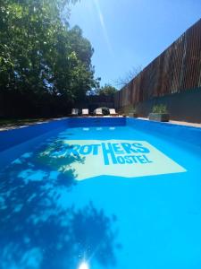 una piscina azul con un cartel que dice que fuera de aquí ha vivido en BROTHERS HOSTEl en Villa Allende