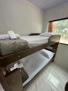 Ce dortoir comprend 2 lits superposés et une fenêtre. dans l'établissement Hospedaria Villa dos Ventos, à Itaúnas