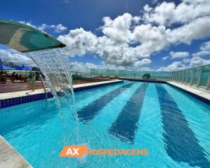 a fountain in the middle of a swimming pool at AX Blue Suítes in João Pessoa