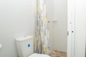 a bathroom with a toilet and a shower curtain at La Niña Mire in Puerto Colombia