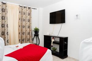 een slaapkamer met een bed met een rode deken en een televisie bij La Niña Mire in Puerto Colombia