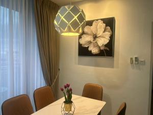 a dining room with a table with a vase of flowers on it at Roxy Apartment Kuching in Kuching