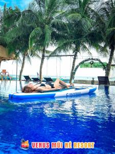 una mujer tumbada en una tabla de paddle en una piscina en Venus MuiNe, en Mui Ne