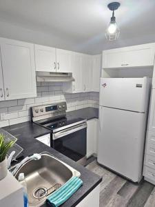 a kitchen with a sink and a white refrigerator at Spacieux Appartement de 3 Chambres downtown in Montreal
