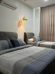 a bedroom with two beds and a couch at Roxy Apartment Kuching in Kuching