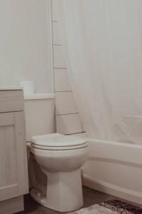 a white bathroom with a toilet and a bath tub at Spacieux Appartement de 3 Chambres downtown in Montreal