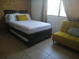 a bedroom with a bed and a couch and a window at La Luna in Cancún