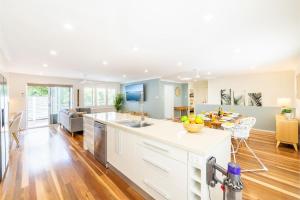 Il comprend une cuisine ouverte et un salon avec une table. dans l'établissement Tropicality - Private family retreat with solar heated pool, à Nelson Bay