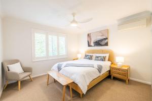 une chambre avec un lit et une chaise dans l'établissement Tropicality - Private family retreat with solar heated pool, à Nelson Bay 32 autres photos