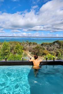 a man in a swimming pool overlooking the ocean at black + shack in Coles Bay