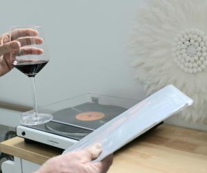 a person holding a glass of wine next to a record player at black + shack in Coles Bay