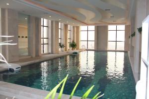a large swimming pool in a building with windows at Ramada Plaza Weifang in Weifang
