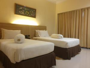 a hotel room with two beds with white sheets at Violand Garden Hotel Samarinda in Samarinda