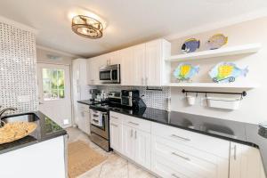 a kitchen with white cabinets and a stove top oven at Happy Camper Cottage - Cozy Oasis with Hot Tub in Palm Harbor