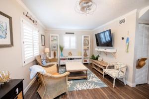 uma sala de estar com uma televisão e um sofá e cadeiras em Happy Camper Cottage - Cozy Oasis with Hot Tub em Palm Harbor