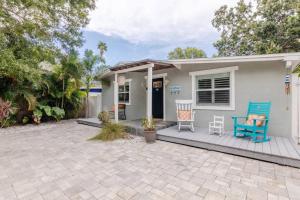 uma pequena casa com um alpendre e duas cadeiras azuis em Happy Camper Cottage - Cozy Oasis with Hot Tub em Palm Harbor