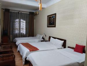 a hotel room with three beds and a window at Holiday Home in Hanoi