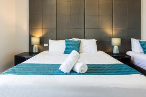 um quarto com duas toalhas brancas numa cama em The Abbott Boutique Hotel em Cairns