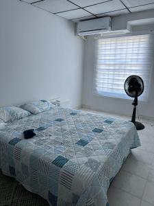 1 dormitorio con 1 cama, ventana y ventilador en Casa Tamarielys, en Cartagena de Indias