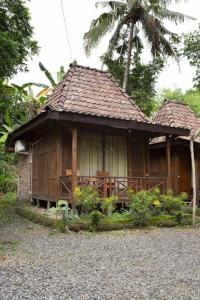 ein kleines Holzhaus mit einer Palme dahinter in der Unterkunft puunee guest house & restaurant in Mendut