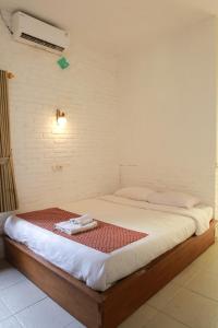 Bett in einem Raum mit Avertisementatronatronatronstrationion in der Unterkunft puunee guest house & restaurant in Mendut