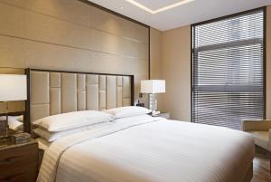 Un dormitorio con una cama blanca grande y una ventana en The Fairway Place, Xi'an - Marriott Executive Apartments, en Xi'an