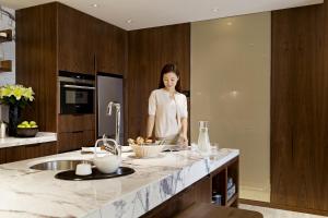 a woman standing in a kitchen with a counter at The Fairway Place, Xi'an - Marriott Executive Apartments in Xi'an