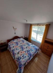 1 dormitorio con 1 cama con edredón de flores y ventana en Cabaña 4 a 5 Pers Los Ángeles, en San Carlos de Purén