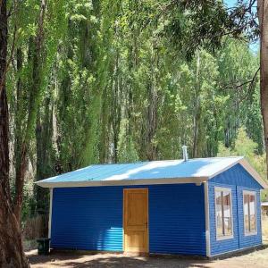 Un cobertizo azul con una puerta en un bosque en Cabaña 4 a 5 Pers Los Ángeles, en San Carlos de Purén