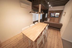 een eetkamer met een houten tafel en witte stoelen bij HISORI Arts and Stay in Kanazawa