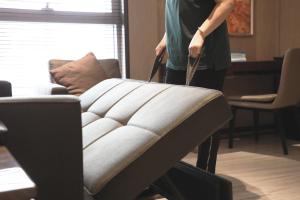 a woman is pulling a couch in a living room at The Fairway Place, Xi'an - Marriott Executive Apartments in Xi'an