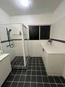 uma casa de banho com chuveiro e piso em azulejo preto em Bet you’ll love butler em Mount Isa
