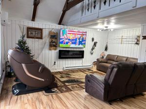 ein Wohnzimmer mit einem Sofa und einem TV in der Unterkunft Cozy Indian Lake Chalet on Golf Course with Arcade/Gameroom in Stoystown